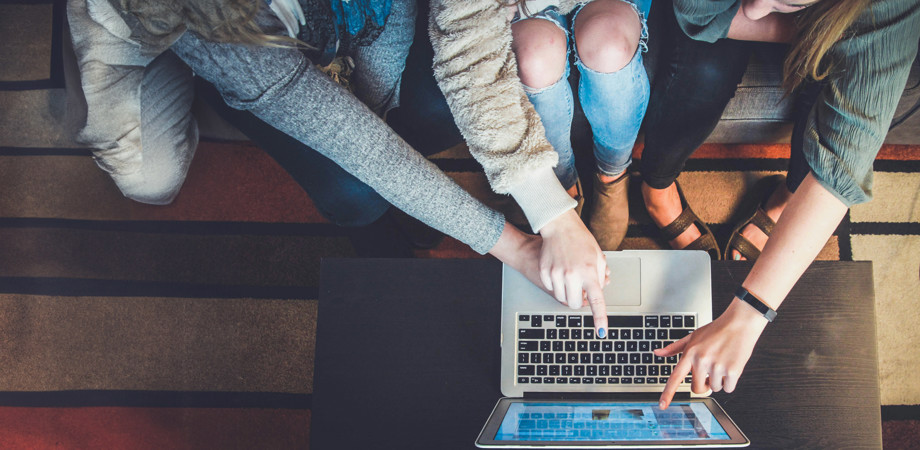 Close up of a group of young people looking at a laptop screen