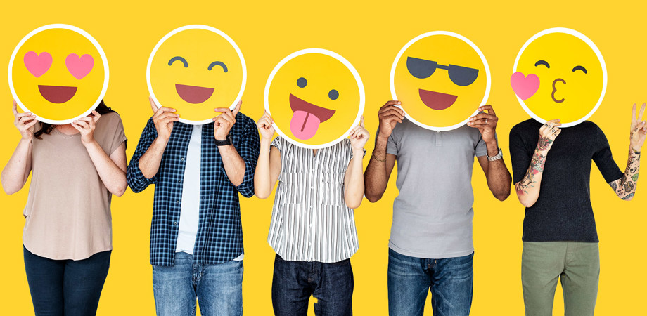 A group of five people holding up emojis in front of their faces