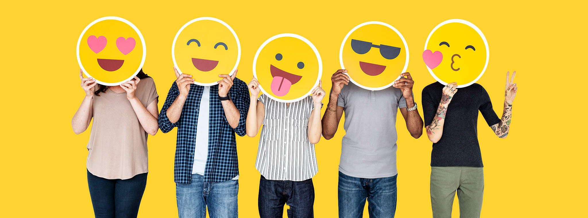 A group of five people holding up emojis in front of their faces