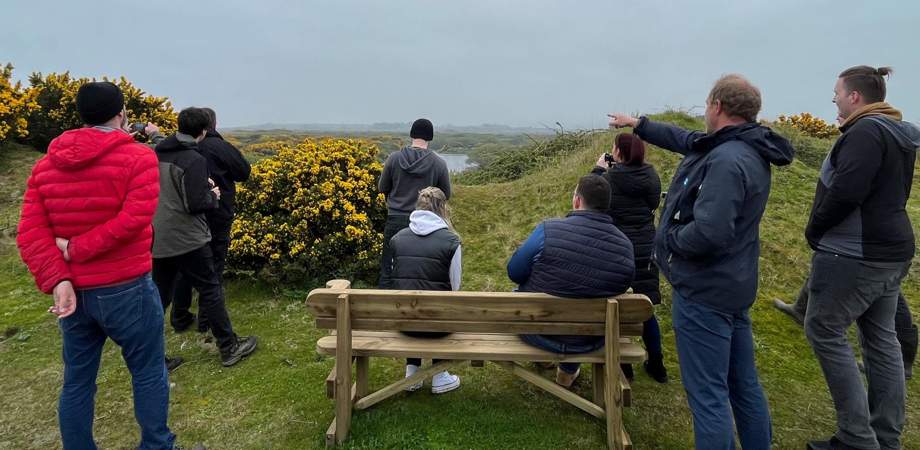 Group of people stood outside in a nature reserve looking out into the distance