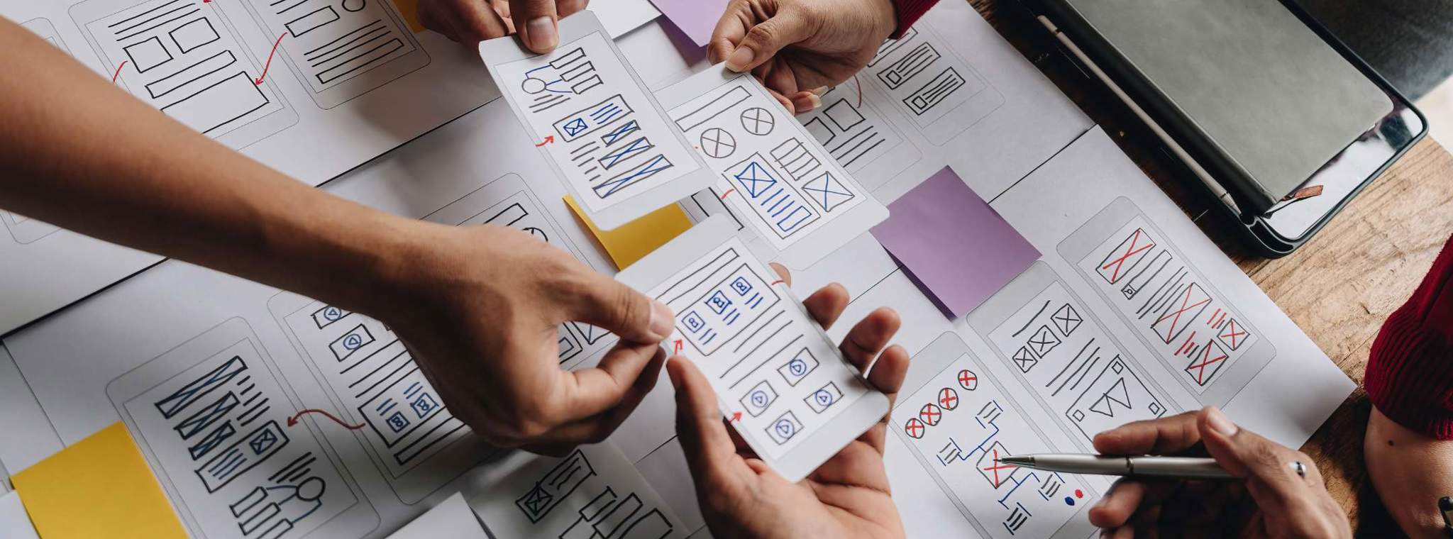 Hands moving pieces of paper with UX design concepts on them