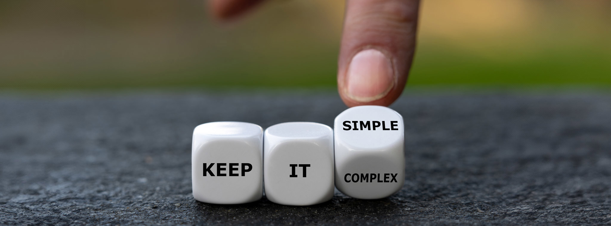 Hand turns dice and changes the expression 'keep it complex' to 'keep it simple'.