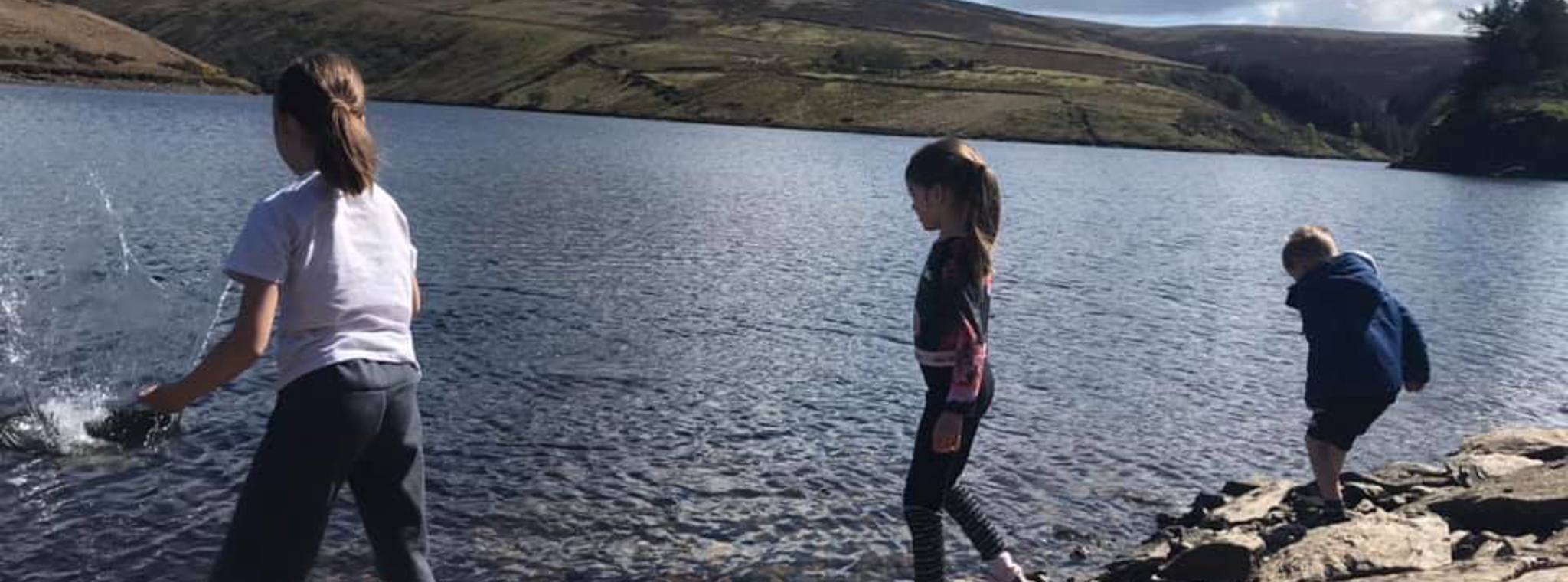 A picture of Kathryn's children throwing stones into a reservoir 