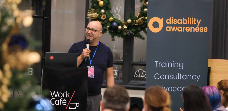 An image of Andy Hodkin speaking at a podium with a microphone