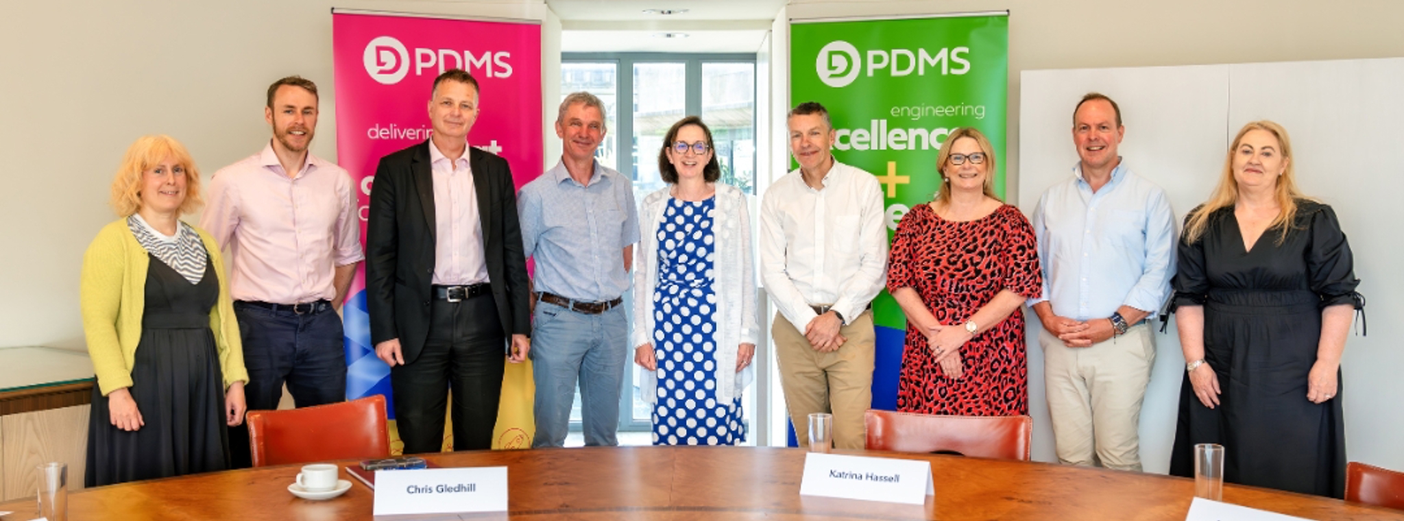 A group of people posing for photo in front of two PDMS banners