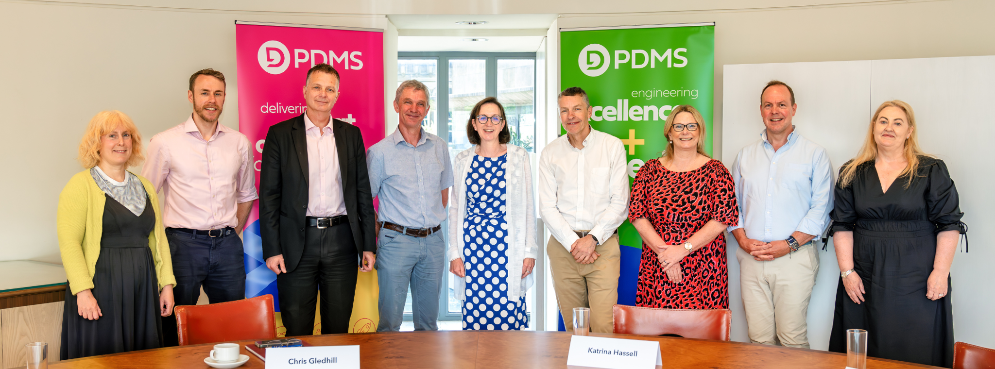 A group of people posing for photo in front of two PDMS banners