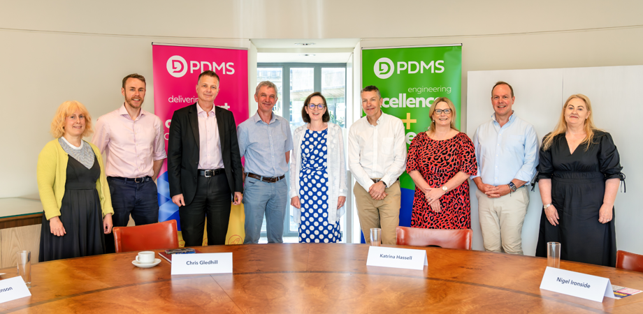 A group of people posing for photo in front of two PDMS banners