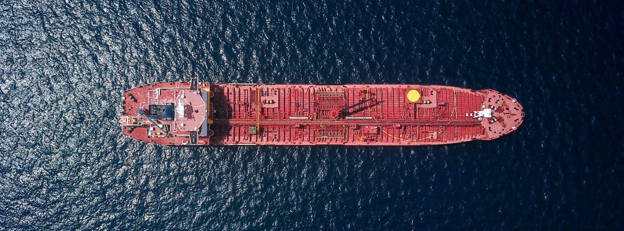 An overhead image of a red container ship on a dark ocean