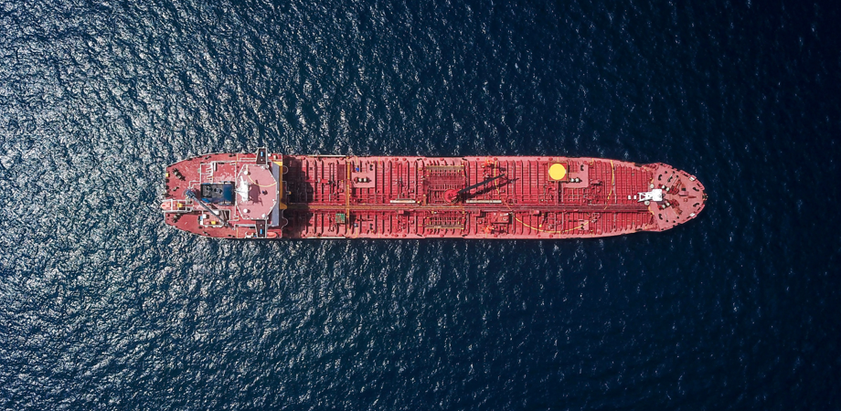 An overhead image of a red container ship on a dark ocean