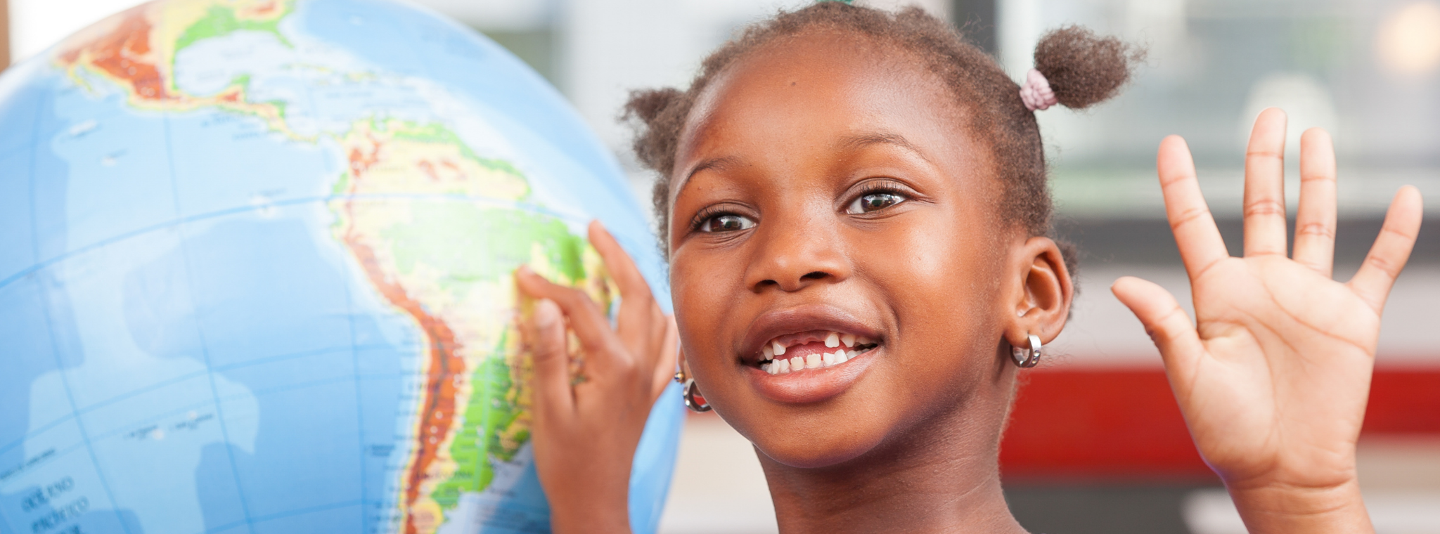 An image of a little girl pointing at South America on a globe