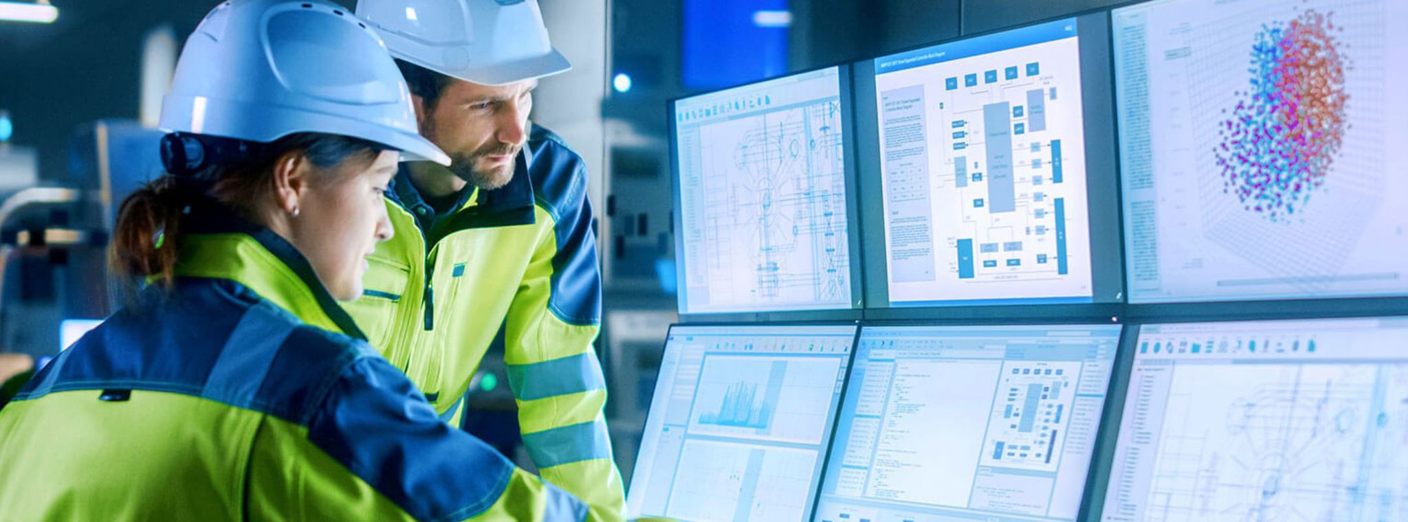 Two manufacturing workers using several screens of IT systems