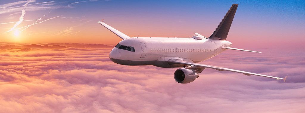 Plane flying through sunset sky with clouds