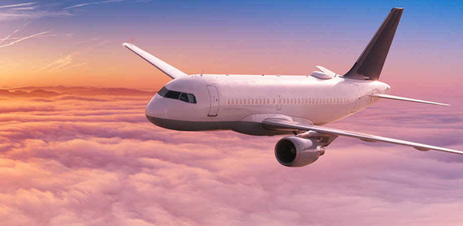 Plane flying through sunset sky with clouds