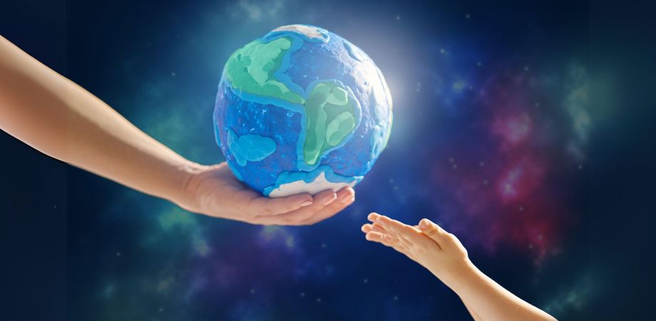 An image of an adult hand holding out a globe to a child's hand with a starry background