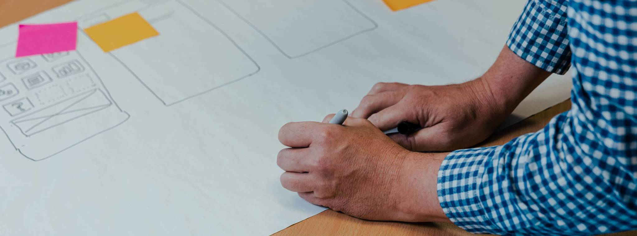 Two hands writing on a piece of paper with post-it notes attached