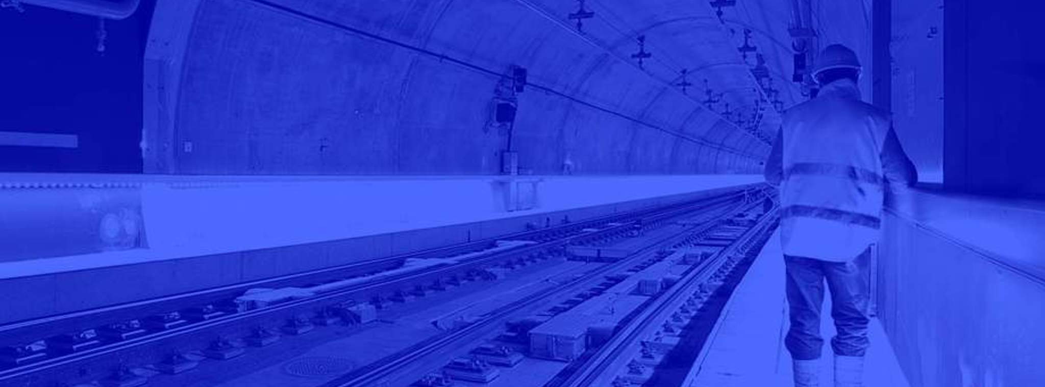 Duotone blue image of engineer working in a train tunnel 