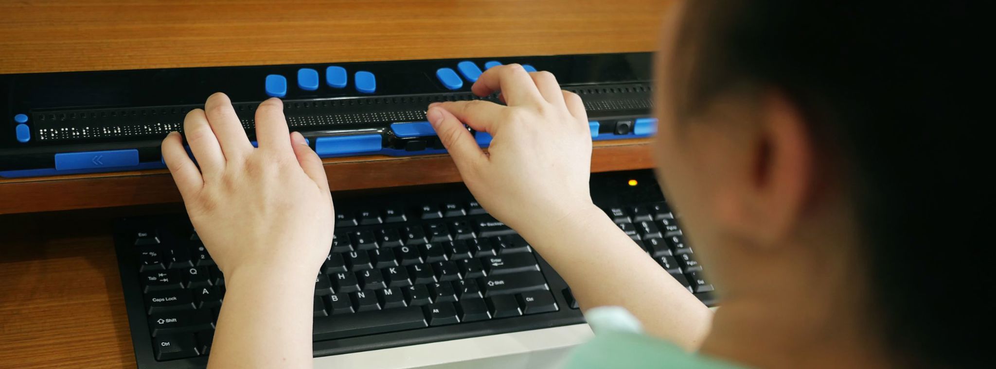 An image of a person using a braille keyboard for a computer