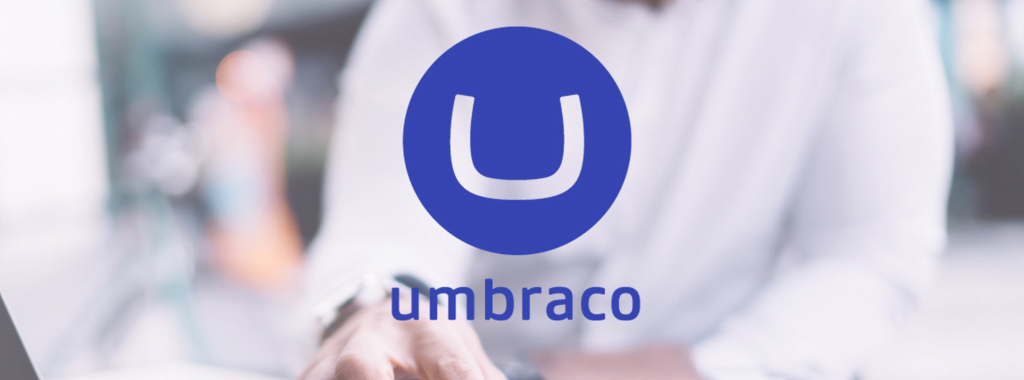 Developer using a laptop in the background with Umbraco logo